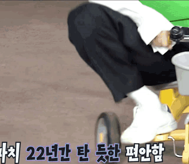 a person is riding a yellow tricycle with korean writing on the side