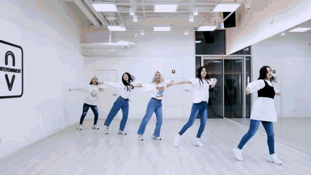 a group of women are dancing in front of a mirror in a dance studio with the letter c on the wall