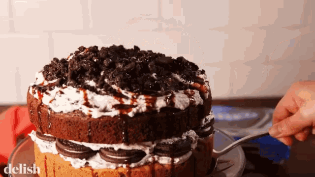 a chocolate cake with oreos and whipped cream is being eaten with a fork