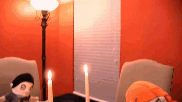 two stuffed animals are sitting at a table with candles and a lamp