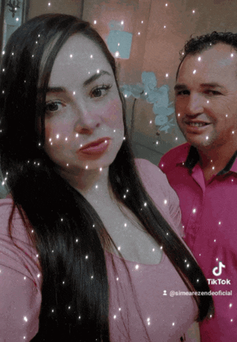a man and a woman are posing for a picture and the woman is wearing a pink shirt and the man is wearing a red shirt