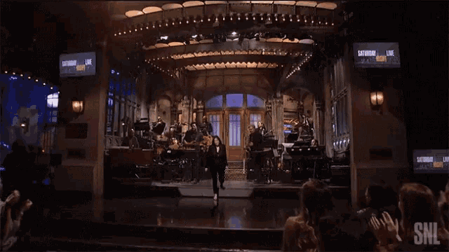 a woman is standing on a stage in front of a snl logo