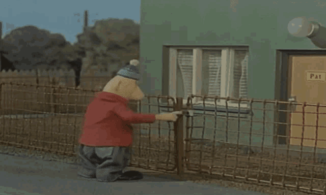 a cartoon character standing next to a fence with a pat sign on the door