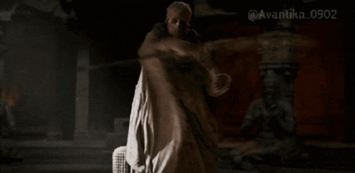 a man in a white robe is dancing in front of a statue with the numbers 0902 on the bottom