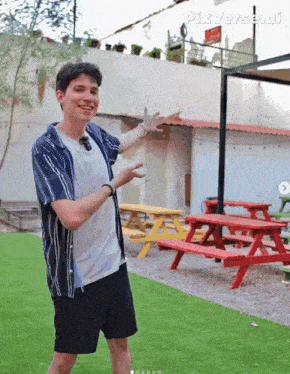 a man standing in front of red picnic tables with pixverse ai written on the bottom right