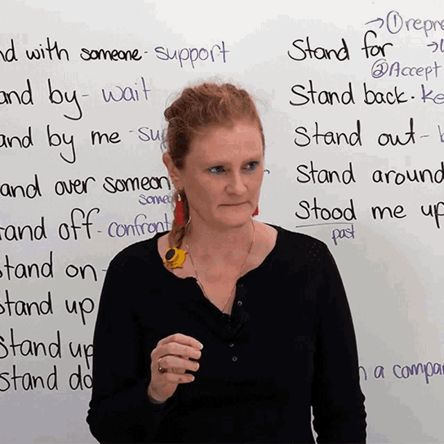 a woman stands in front of a white board that says stand for