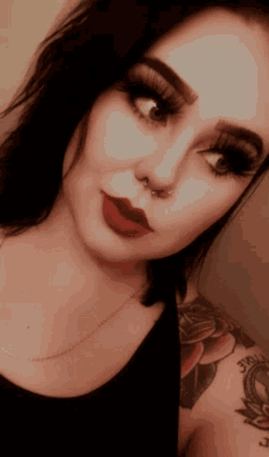 a woman with a nose ring and red lipstick looks at the camera