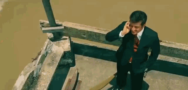 a man is sitting in a chair talking on a cell phone and laughing .