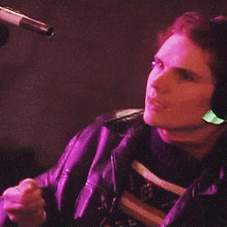 a man wearing headphones plays a guitar in front of a microphone
