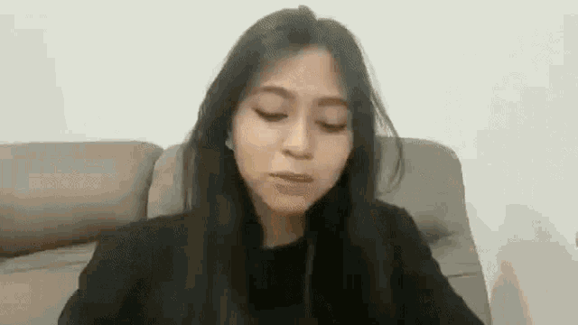 a woman is sitting on a couch with her eyes closed and making a funny face .