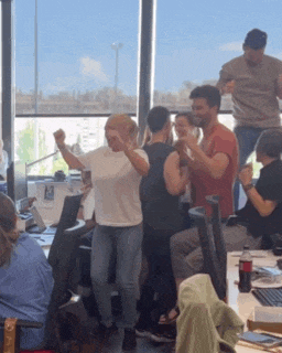 a group of people are dancing in a room with a coca cola bottle in the foreground