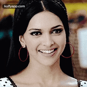 a close up of a woman wearing hoop earrings and smiling
