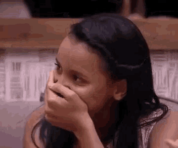 a woman is covering her mouth with her hand .