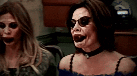 two women wearing sunglasses and a choker are standing next to each other .