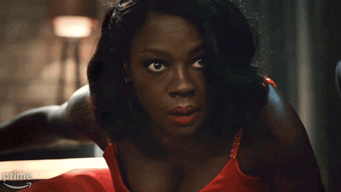 a woman in a red dress is sitting at a table with an amazon prime arrow in the background