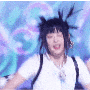 a woman wearing a white shirt and a backpack is dancing on a stage with her eyes closed .