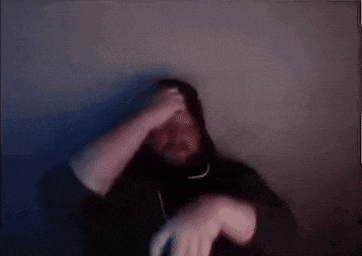 a blurry picture of a man in a black hoodie holding his head .