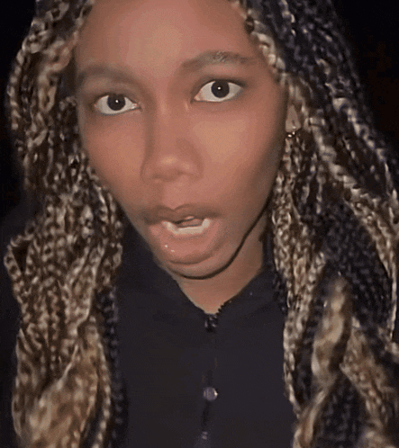 a close up of a woman 's face with braids on her hair