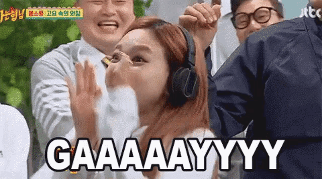a woman wearing headphones is standing in front of a group of people and making a face .