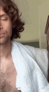 a man with long curly hair is wearing a white towel around his neck .