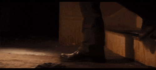 a close up of a person 's feet in a dark room wearing black shoes .