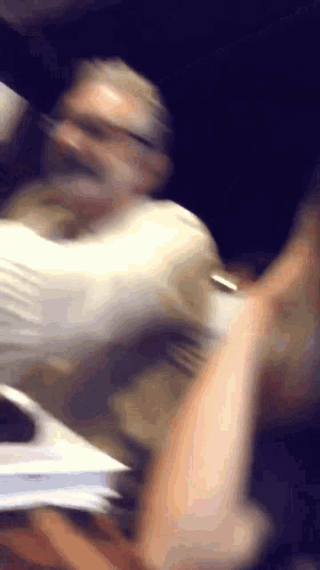 a blurry picture of a man in a white shirt and glasses