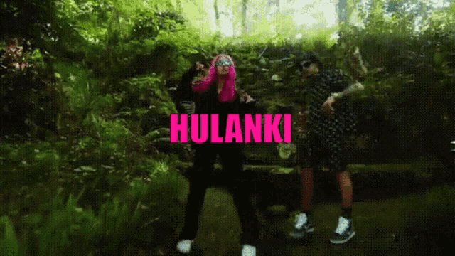 a woman with pink hair is dancing in the woods with the word hulanki in pink letters