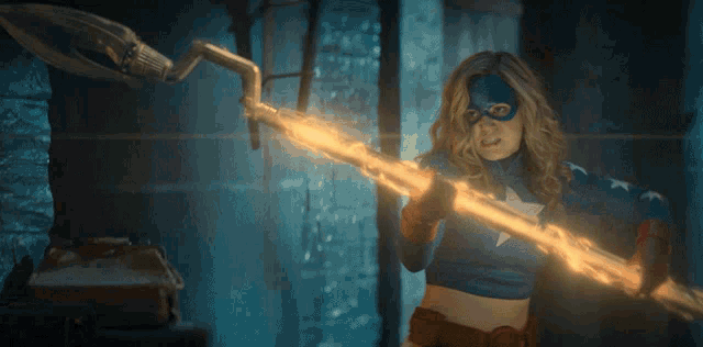 a woman in a superhero costume is holding a glowing spear