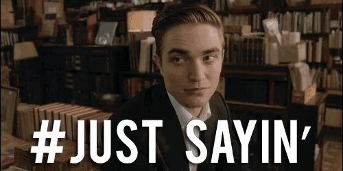 a man in a suit says " just sayin " in front of a library full of books