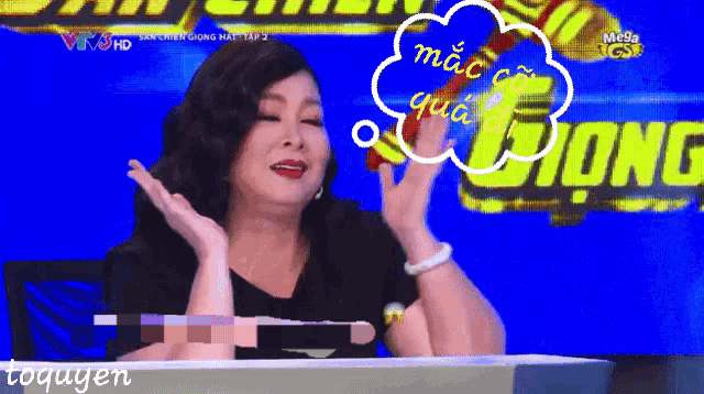 a woman is sitting at a table with a speech bubble that says mac co qua da dong