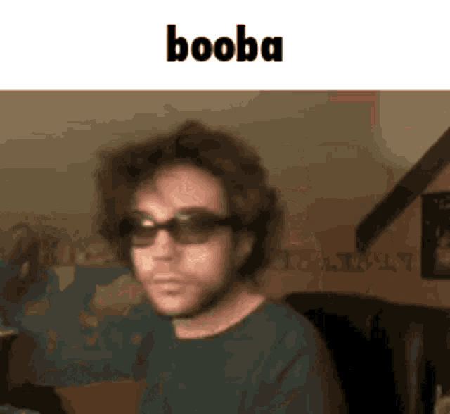 a man wearing sunglasses is making a funny face with the word booba written above him .