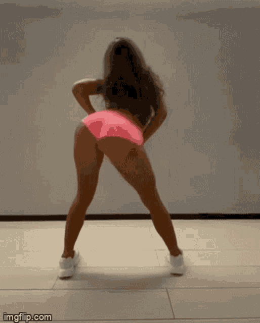 a woman wearing pink shorts and a white top is dancing