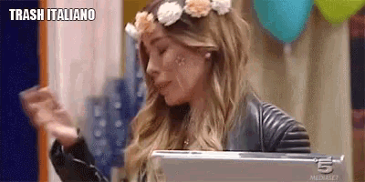 a woman wearing a flower crown and a leather jacket is holding a laptop .