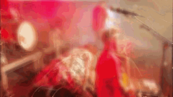 a blurry picture of a man in a red shirt playing a drum