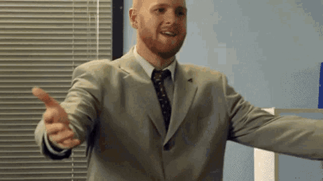 a man in a suit and tie is giving a thumbs up .