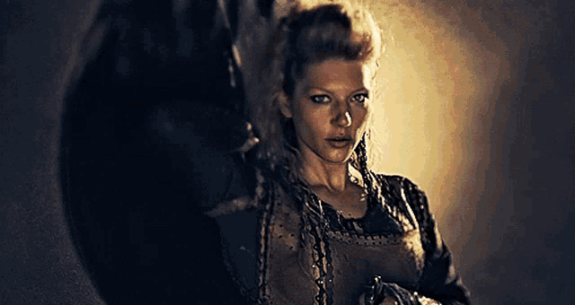 a woman with braids in her hair holds a sword in her hand