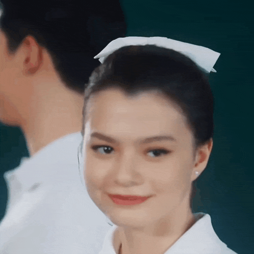 a close up of a woman wearing a white nurse 's cap and smiling .