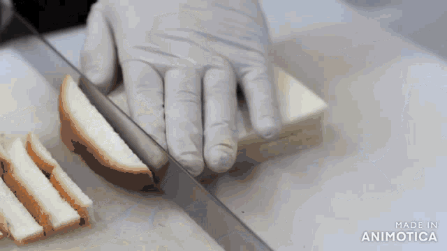 a person is cutting a piece of bread on a cutting board with the words made in animatica visible