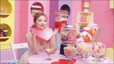 a woman sitting at a table with a candy machine that says cherry bubble gum