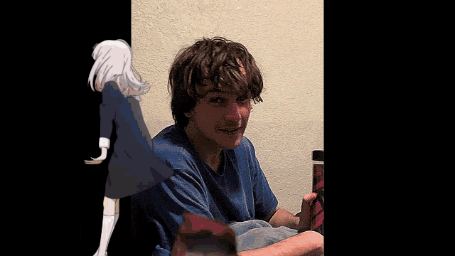 a man in a blue shirt is sitting in front of a wall with a drawing of a girl behind him