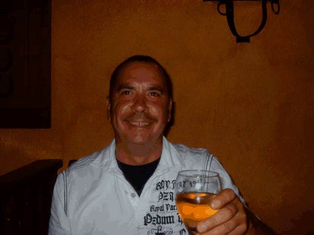 a man wearing a shirt that says royal park on it is holding a glass of beer
