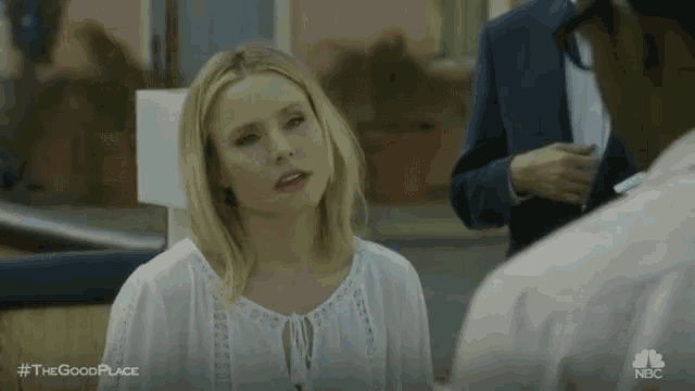 a woman in a white shirt is talking to a man in a blue suit .