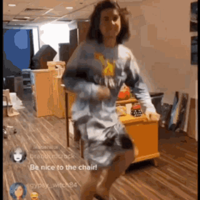 a man in a blue shirt is dancing in a room with a yellow dresser in the background .