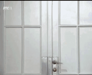 a woman in a white shirt is opening a door