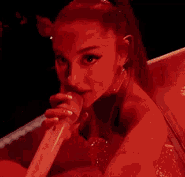 a woman in a red dress is holding a microphone .