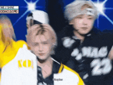 a group of young men are dancing on a stage and one of them is wearing a yellow jacket with the number 20 on it