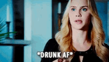 a woman with blonde hair is holding a bottle and saying " drunk af " .