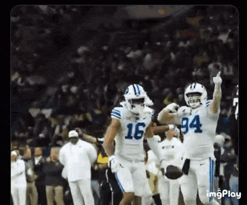two football players , one wearing the number 16 and the other wearing the number 94 , are celebrating a touchdown on the field .