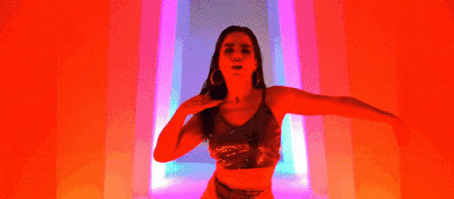 a woman is standing in front of a neon sign in a dark room .