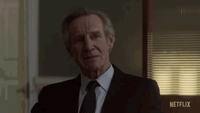 a man in a suit and tie stands in front of a netflix logo